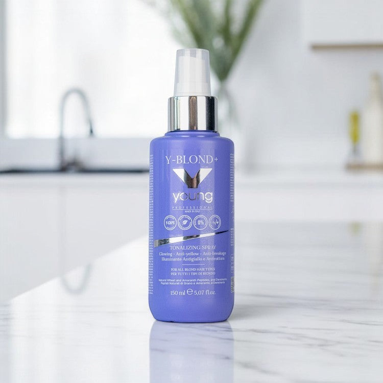 John Hair Young Y-Blond+ purple leave-in toning spray for blonde hair in a 150ml bottle on a marble surface.